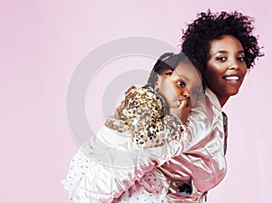 young pretty african-american mother with little cute daughter hugging, happy smiling on pink background, lifestyle