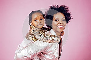 Young pretty african-american mother with little cute daughter hugging, happy smiling on pink background, lifestyle