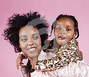 Young pretty african-american mother with little cute daughter hugging, happy smiling on pink background, lifestyle