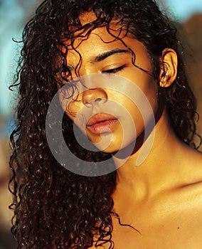 Young pretty african curly girl on sunset on beach looking, lifestyle people concept