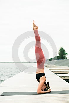 Young Pretty asian girl doing yoga outdoors on the pier by the lake