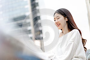 Young pretty Asian girl listening to music on earphones