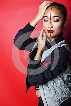 Young pretty asian girl posing cheerful on red background, fashion makeup and clothers