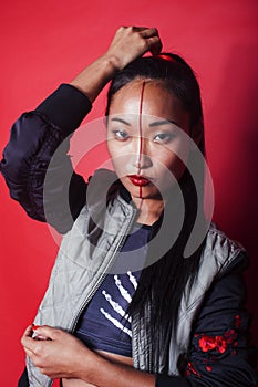 Young pretty asian girl posing cheerful on red background, fashion makeup and clothers