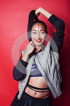 young pretty asian girl posing cheerful on red background, fashion makeup and clothers
