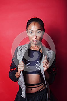 young pretty asian girl posing cheerful on red background, fashion makeup and clothers