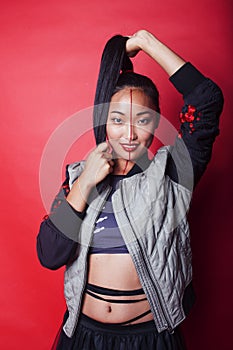 young pretty asian girl posing cheerful on red background, fashion makeup and clothers