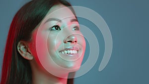 Young pretty asian woman looking at free space and sincerely smiling, expressing inspiration, blue studio background