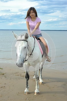 Young pretty asian woman riding white horse