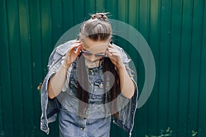 Young pretty attractive girl in denim clothes in glasses on a simple dark green background with place for text