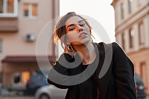 Young pretty beautiful woman in a black stylish t-shirt in a vintage coat with natural make-up with sexy lips near vintage houses