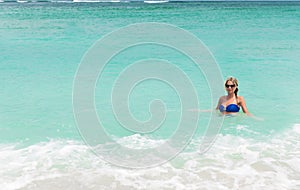 Young pretty blond woman in blue bikini on white tropic beach