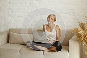 Young pretty blond woman freelancer working from home using laptop or notebook.