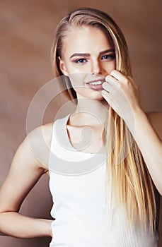 Young pretty blond woman with fresh natural makeup posing cheerful on browm background, lifestyle people concept