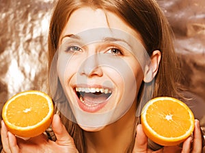 Young pretty blond woman with half oranges close up on white bright teenage smiling