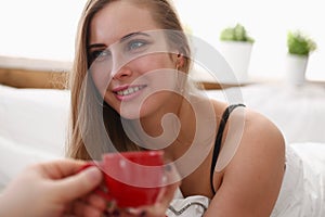 Blond woman have cup of tea coffee early morning in her bed