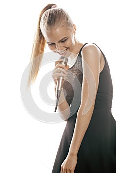 Young pretty blond woman singing in microphone