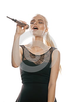 Young pretty blond woman singing in microphone