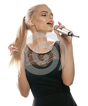 Young pretty blond woman singing in microphone isolated close up black dress, karaoke girl
