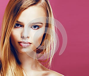 young pretty blonde real woman with hairstyle close up and makeup on pink background smiling