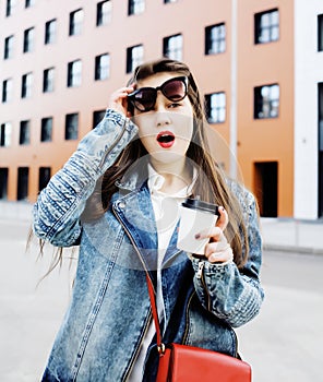 young pretty brunette business woman posing against modern building in hat holding coffee, lifestyle people concept