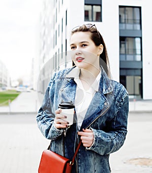 young pretty brunette business woman posing against modern building in hat holding coffee, lifestyle people concept