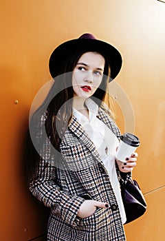 young pretty brunette business woman posing against modern building in hat holding coffee, lifestyle people concept