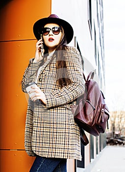 young pretty brunette business woman posing against modern building in hat holding coffee, lifestyle people concept