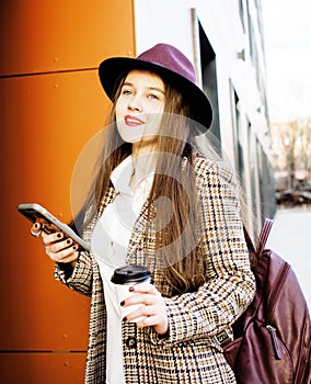 young pretty brunette business woman posing against modern building in hat holding coffee, lifestyle people concept