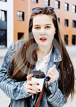 young pretty brunette business woman posing against modern building in hat holding coffee, lifestyle people concept