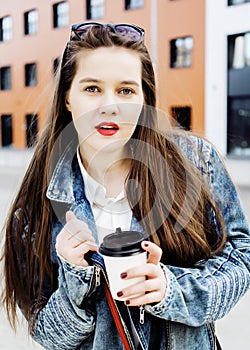 young pretty brunette business woman posing against modern building in hat holding coffee, lifestyle people concept