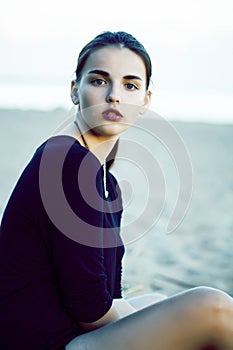 Young pretty brunette girl with long hair waiting alone on sand at seacoast, lifestyle people concept