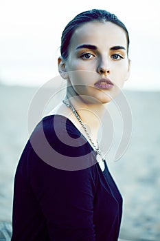 Young pretty brunette girl with long hair waiting alone on sand at seacoast, lifestyle people concept