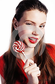 Young pretty brunette girl with red candy posing on white background isolated