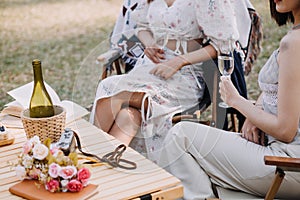 Young pretty brunette twin girls sitting on the grass with legs slightly bent in knees and looking in a brown book, wearing casual