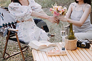 Young pretty brunette twin girls sitting on the grass with legs slightly bent in knees and looking in a brown book, wearing casual