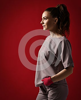 Young pretty brunette woman doctor gynecologist in red latex gloves and medical uniform stands looking at copy space