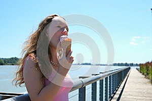 Young Pretty Brunette Woman eating an Ice Cream Cone on a Summer Street