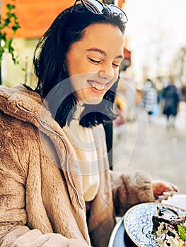Young pretty brunette woman eating ice cream at the street cafe at Paris, France. Outdoor lifestyle portrait.