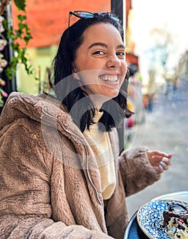 Young pretty brunette woman eating ice cream at the street cafe at Paris, France. Outdoor lifestyle portrait.