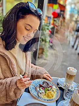 Young pretty brunette woman eating ice cream at the street cafe at Paris, France. Outdoor lifestyle portrait.