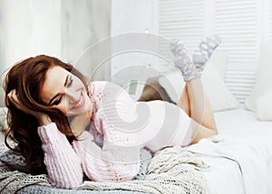 Young pretty brunette woman in her bedroom sitting at window, happy smiling lifestyle people concept