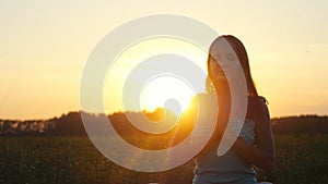 Young pretty brunette woman meditates in nature, in the field during beautiful sunset with lense flare effects
