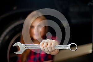 Young pretty brunette woman show wrench. Blur macro