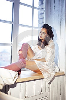Young pretty brunette woman sitting at window at home at morning relaxing, lifestyle people concept