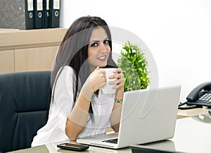 Young pretty business woman having coffee in office