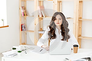 Young pretty business woman with notebook and document in the bright modern office indoors