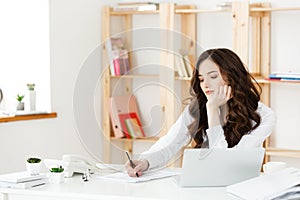 Young pretty business woman with notebook and document in the bright modern office indoors