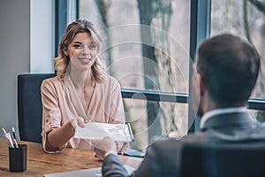 Young pretty business woman taking documents from man