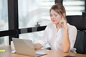 Young pretty business woman working on laptop computer or notebook in the office